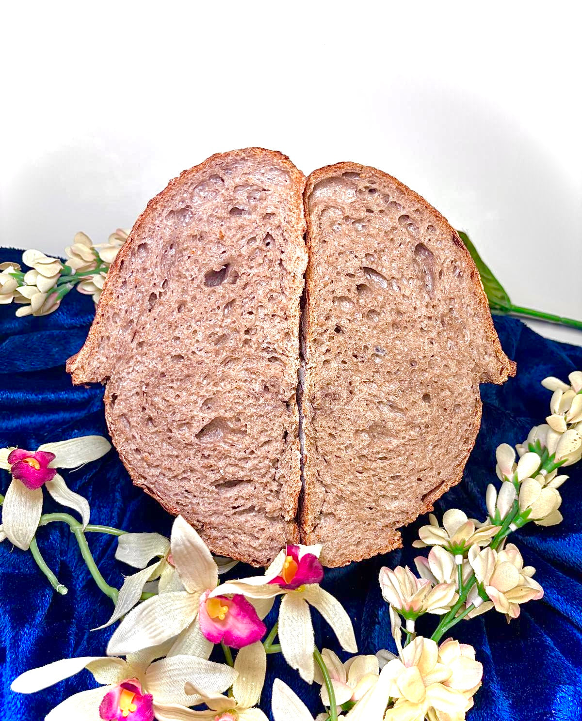 Half-sliced loaf of bread on a blue surface with flowers