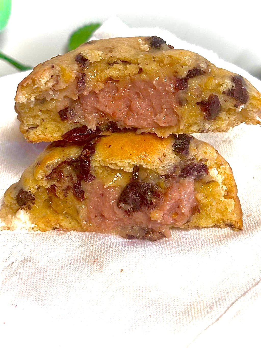 Two halves of a cookie with a pink filling on a white cloth