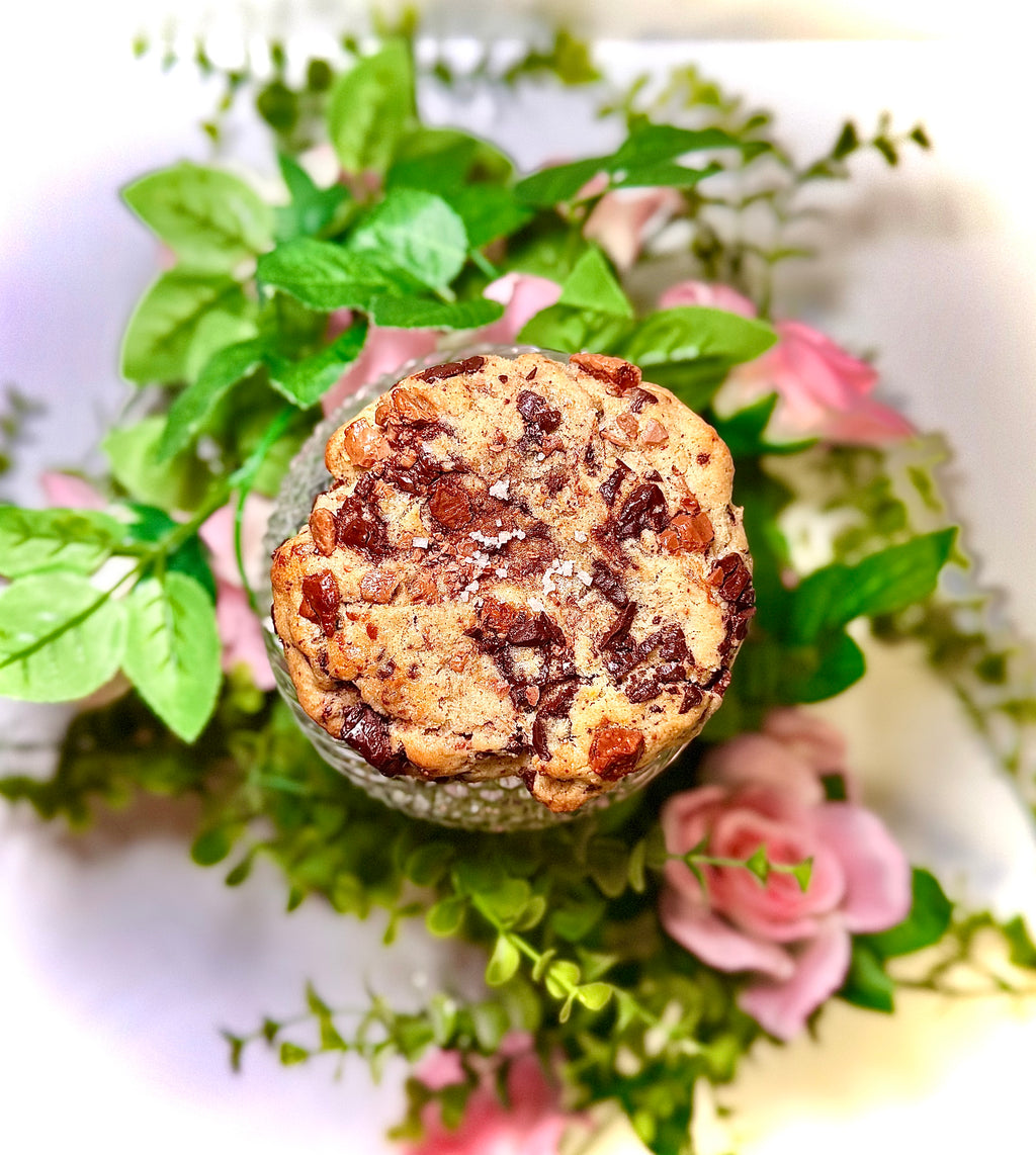 cookie on a glass jar with greenery and flowers on a white background