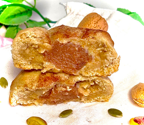 Two halves of a cookie with a soft apple interior on a white cloth background.