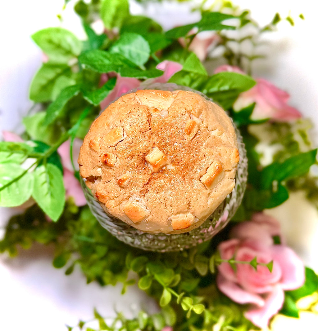 cookie on a glass jar with greenery and flowers on a white background
