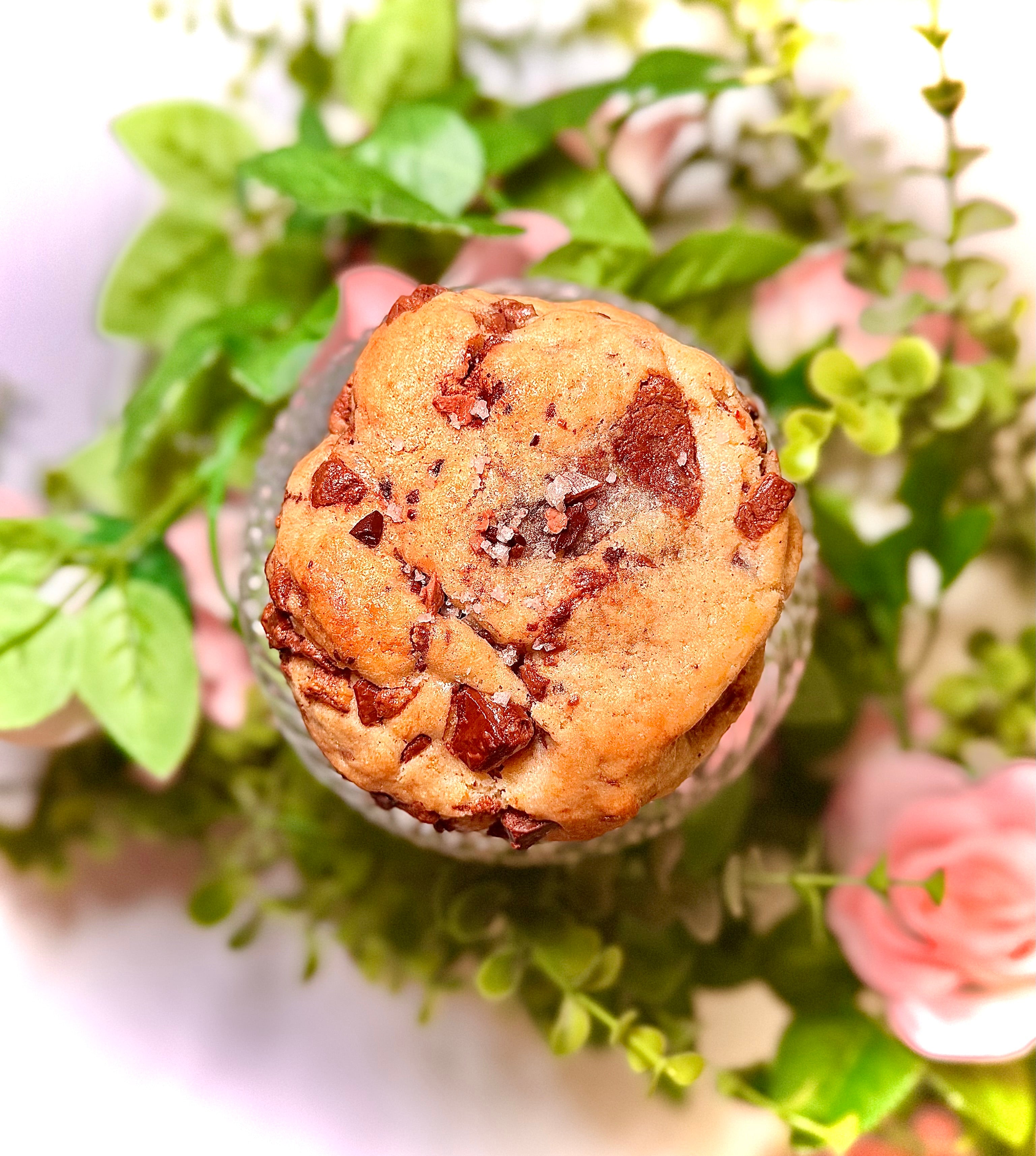 cookie on a glass jar with greenery and flowers on a white background