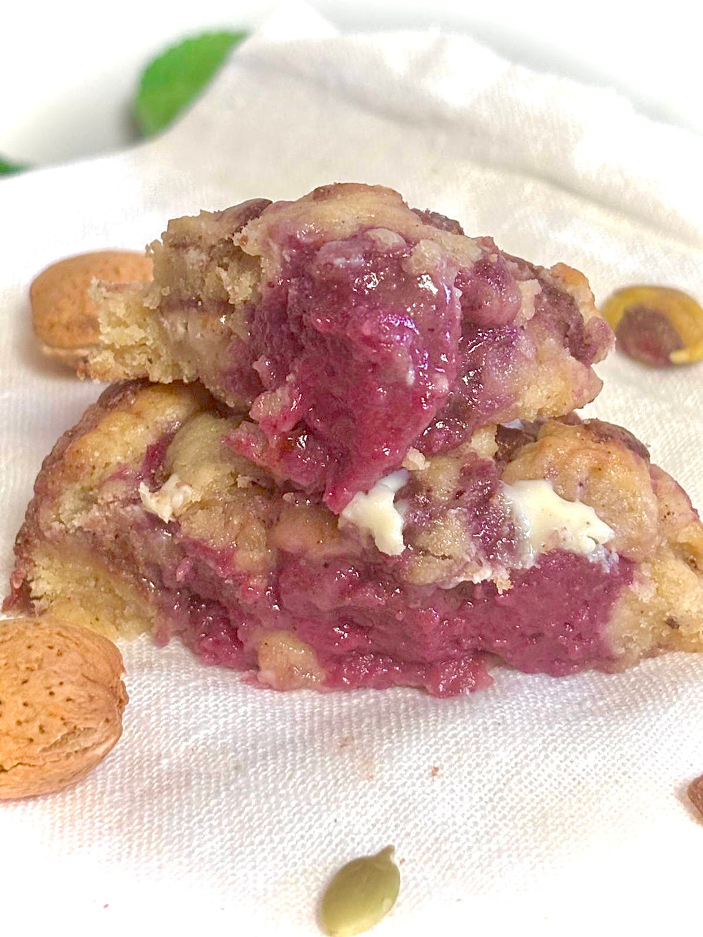 Close-up of a cookie with raspberry filling and almonds on a white cloth