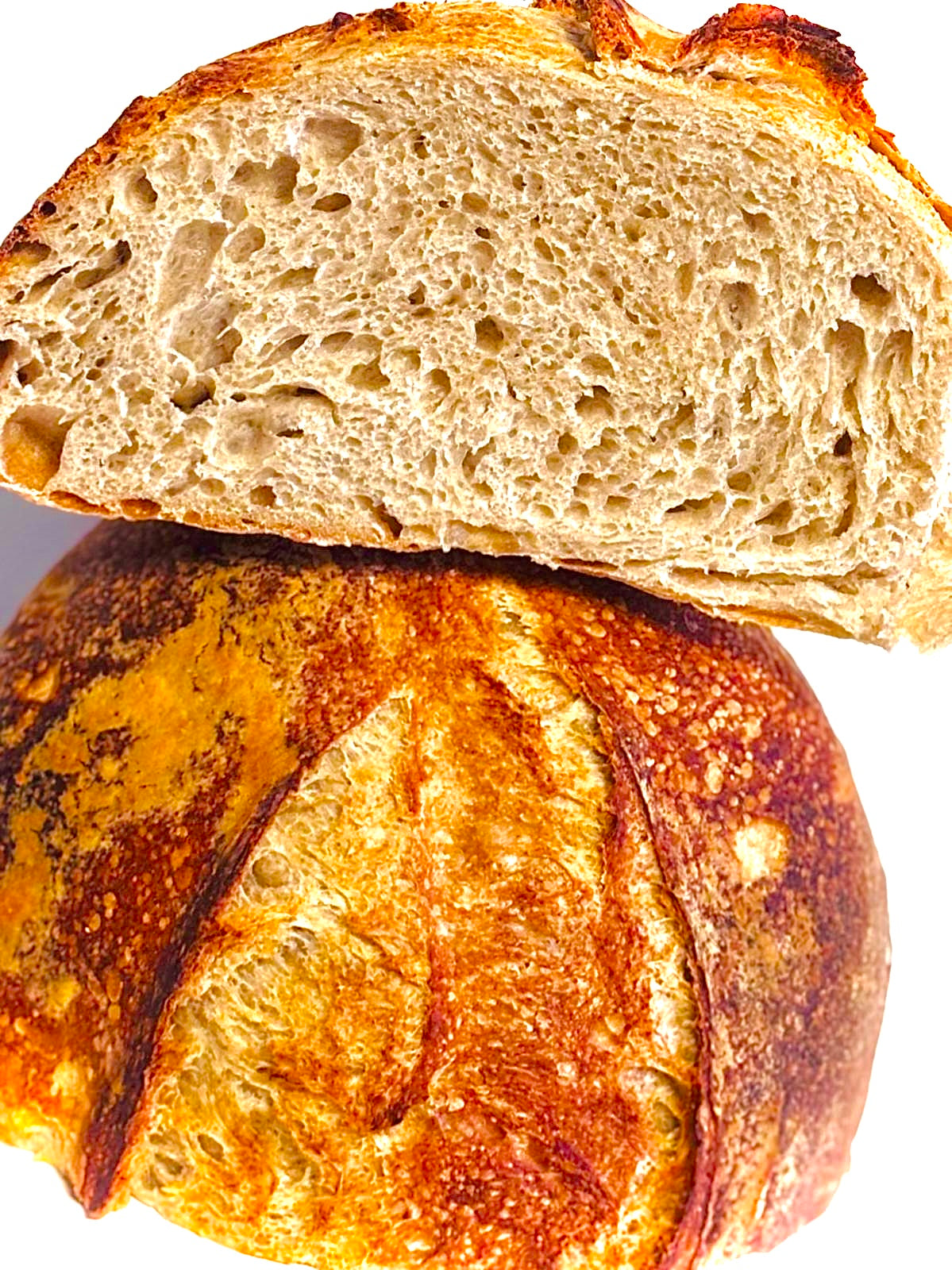 Close-up of a loaf of bread with a slice cut off, showing a porous interior.